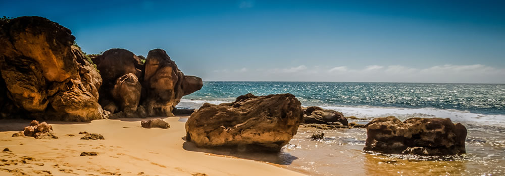 A buetiful coast with bulders lining a sandy shore
